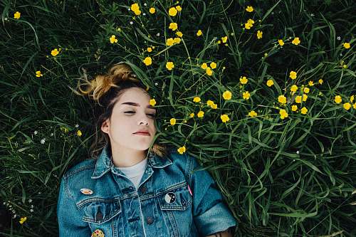 people woman in blue chambray jacket lying on green grass person