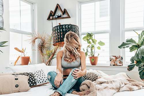 person woman in gray sports bra sitting on bed near windows cushion