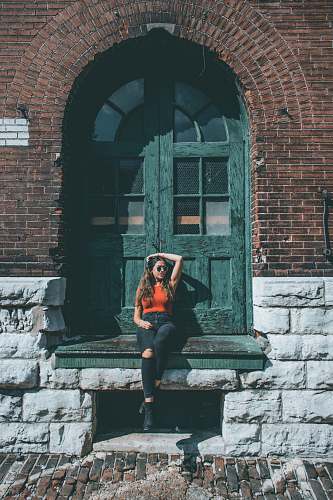 people woman sitting in front of green wooden door person
