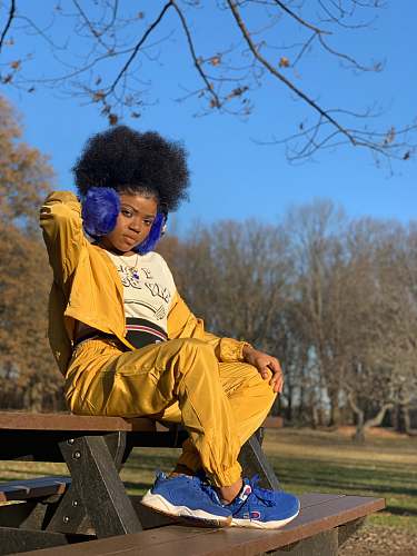 person woman sitting on picnic table under tree during daytime hair