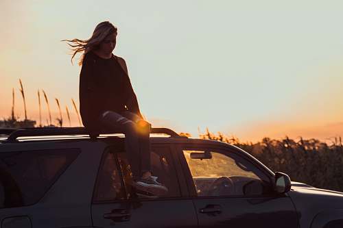 people woman sitting on vehicle roof taken during golden hour person