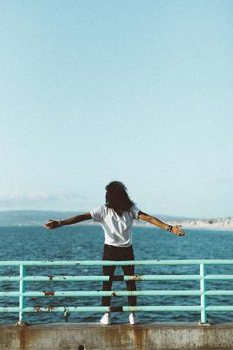 person woman standing in front of sea under clear blue sky people