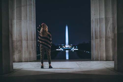 person woman standing inside building facing tower landmark people