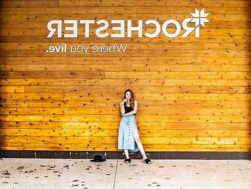 person woman standing on beige tile leaning on brown painted wall people