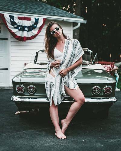people woman standing while leaning on grey car outdoors person