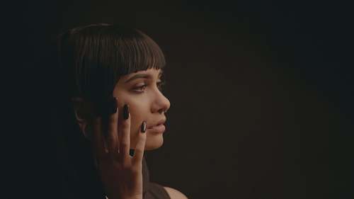 people woman touch her cheek in dim light person