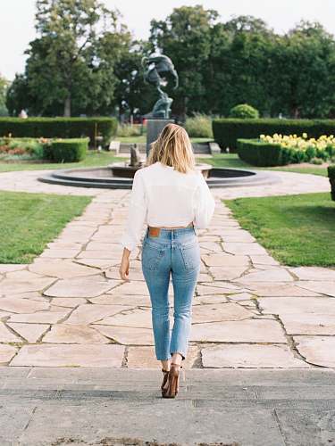 denim woman walking near black water fountain jeans