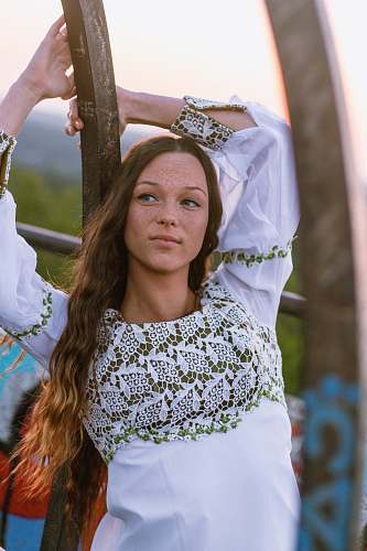 person woman wearing white long-sleeved shirt leaning on black wood plank during daytime people