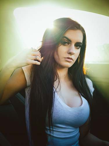 people woman wearing white scoop-neck shirt holding her hair inside car person