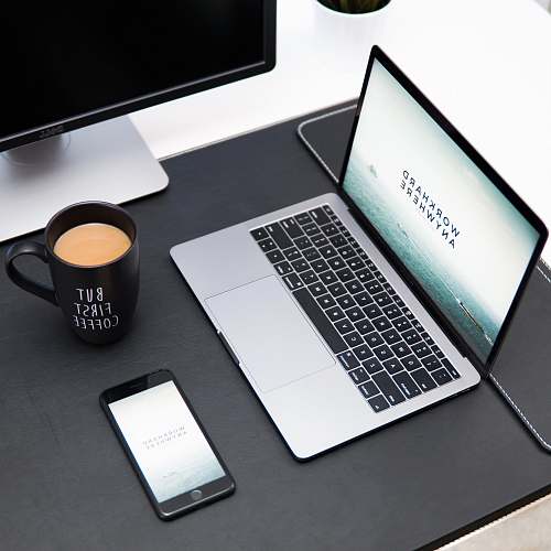cup laptop, coffee mug, and iPhone on desk computer