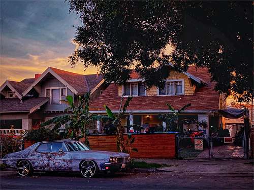 spoke black sedan parked beside brown wooden house during daytime alloy wheel