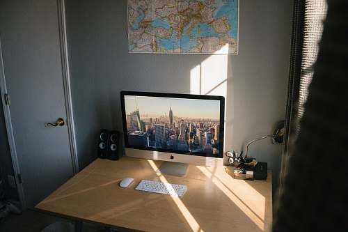 screen turned on silver iMac on beige wooden desk electronics