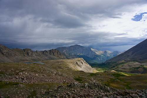 peak green and gray mountains under cloudy sky field