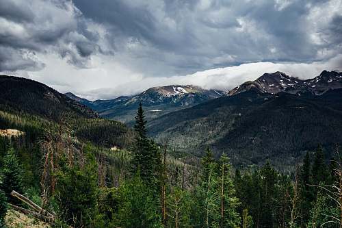 crest mountain and green tress under cloudy sky mountain range