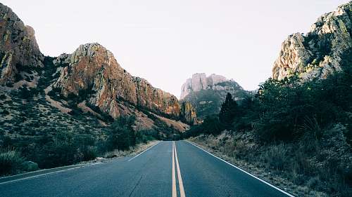 road road lined with rocky mountain at daytime freeway