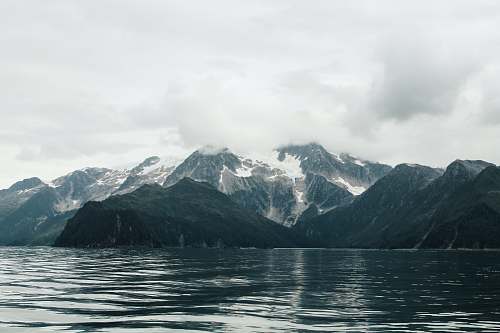 nature snow covered mountain near body of water during daytime outdoors