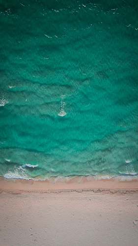 beach aerial photo of green body of water at daytime coast