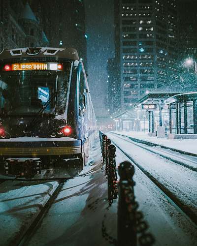 outdoors black and brown train near the building during nighttime snow