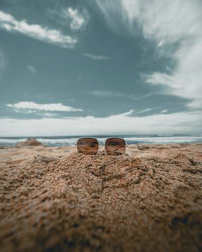 outdoors brown lens sunglasses on sand in low angle photography photography ground