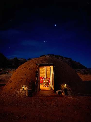 building brown wooden house near brown mountain under blue sky during night time countryside