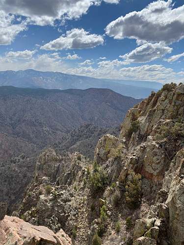 outdoors green trees on brown rocky mountain under blue sky during daytime mountain