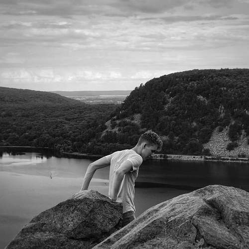 outdoors man leaning on boulder black-and-white