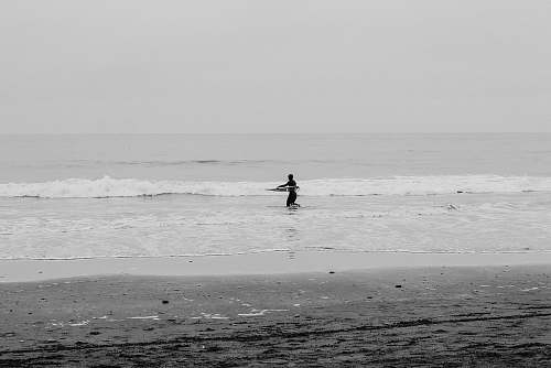 black-and-white man surfboarding at daytime sea
