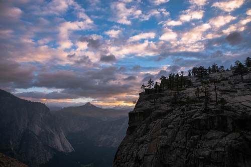 outdoors mountain cliff under cloudy sky during daytime cliff