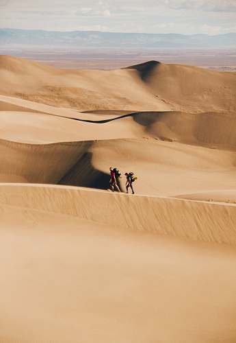 desert people walking in the desert during daytime sand
