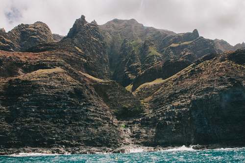 mountain rock mountains near waterfalls under gray sky outdoors