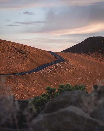 desert selective focus photography of blacktop road at hills outdoors