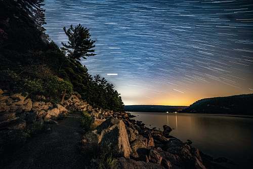 outdoors time-lapse photography of stars above body of water ripple