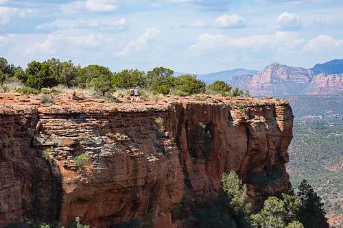 mountain two person walks on brown cliff under clear blue sky during daytime canyon