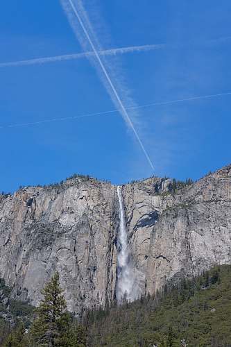 outdoors white contrails on a blue sky and waterfalls river