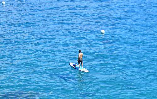 ocean woman in black bikini riding on blue surfboard during daytime water