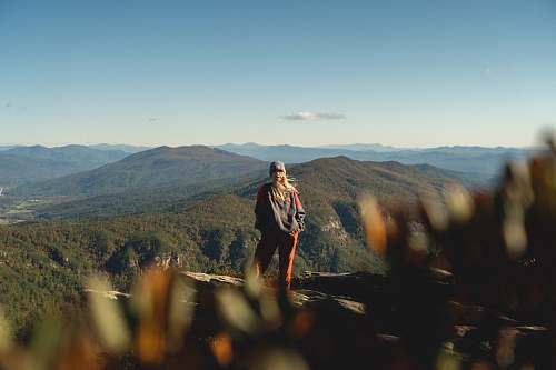 person woman standing on cliff overview of mountain in landscape photography mountain