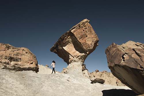 utah woman standing under brown rock formation at daytime rock
