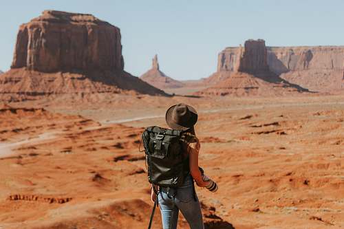 desert woman with black backpack standing on brown dessert outdoors