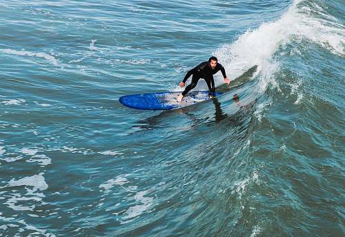 surfing man in black wet suit surfing on wave during daytime person