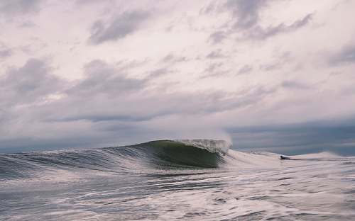 sea surfer on body of water in front of waves at daytime water