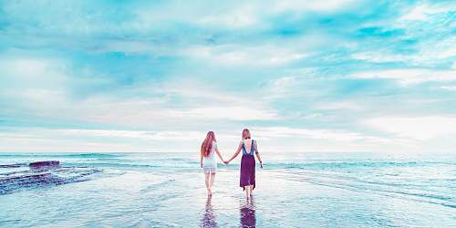 sea two women walking on shoreline holding hands san diego