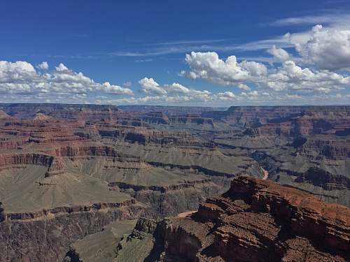 mountain aerial photo of brown and grey mountains under blue cloudy sky photo taken during daytime canyon