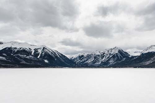 mountain body of water near mountain peak during daytime snow