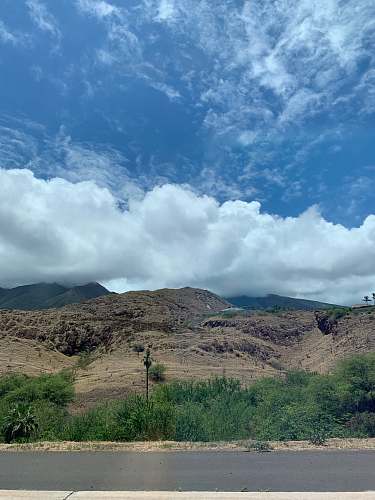 nature green grass field on brown mountain under white clouds and blue sky during daytime countryside