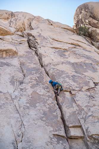 climbing person in blue shirt climbing on brown mountain adventure