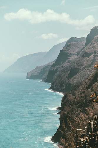 cliff rocky mountains next to ocean water grey