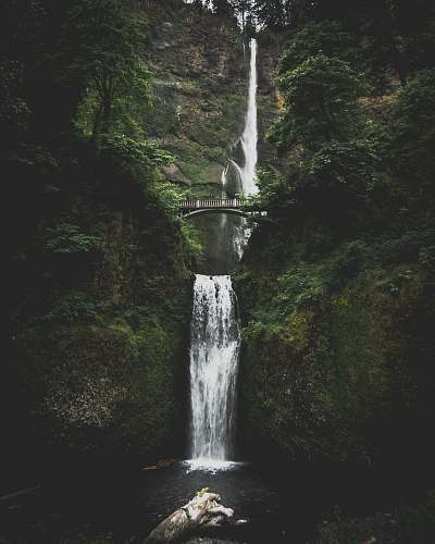 waterfall waterfall in between mountains with bridge river