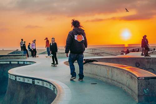 apparel man in black jacket standing on gray concrete floor during sunset clothing