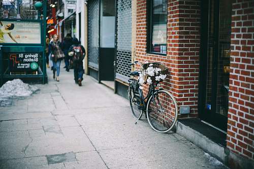 sidewalk black city bicycle parked beside brown concrete brick wall bicycle