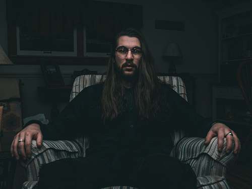 human man in black dress shirt sitting on sofa chair person